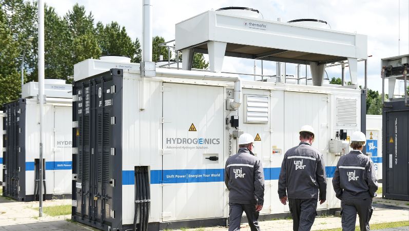 Elektrolyse-Container der Power-to-Gas Anlage Falkenhagen, drei Mitarbeiter gehen daran vorbei